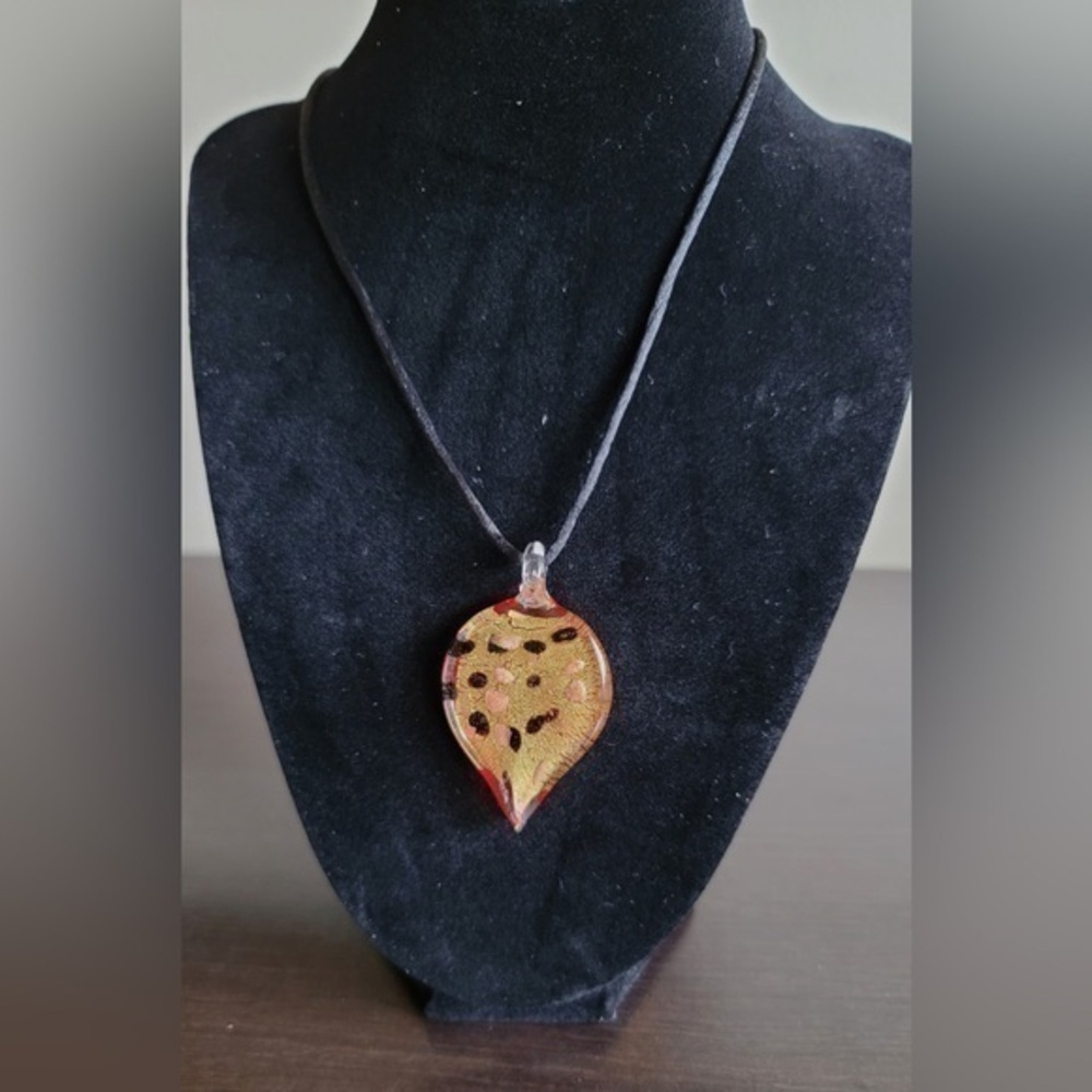 Beautiful red and golden glass pendant on black cord.